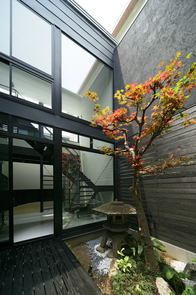 Cette image montre un petit jardin sur cour asiatique avec une terrasse en bois.