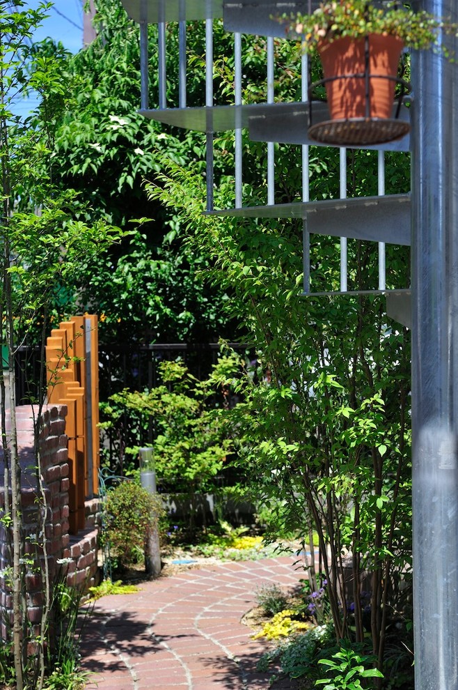 Modelo de jardín minimalista pequeño en primavera en patio delantero con exposición total al sol y adoquines de ladrillo