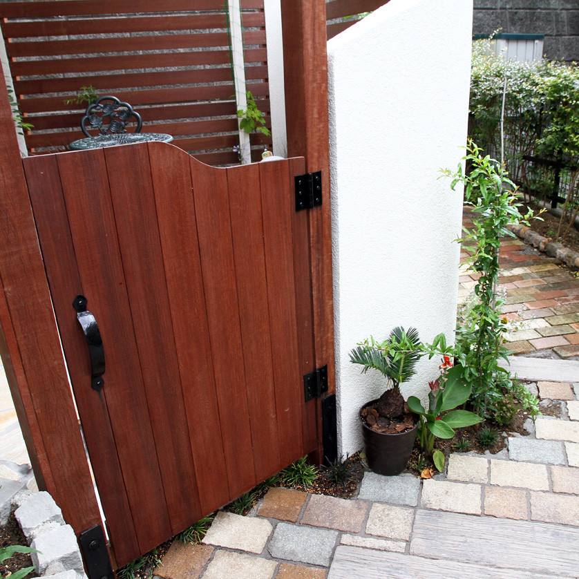 Immagine di un giardino minimalista esposto in pieno sole davanti casa con cancello, pavimentazioni in cemento e recinzione in legno