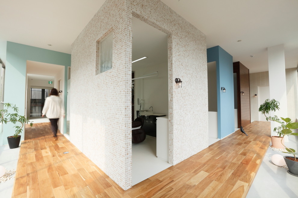 Cette image montre un couloir nordique de taille moyenne avec un mur beige, tomettes au sol et un sol blanc.