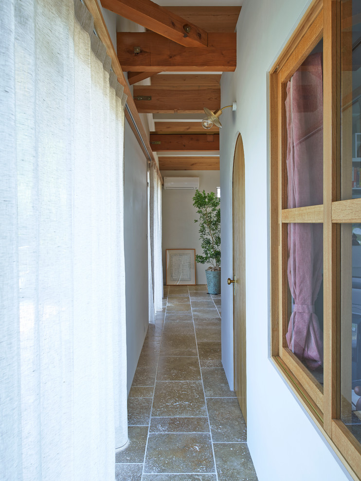 На фото: коридор в средиземноморском стиле с белыми стенами и полом из терракотовой плитки с