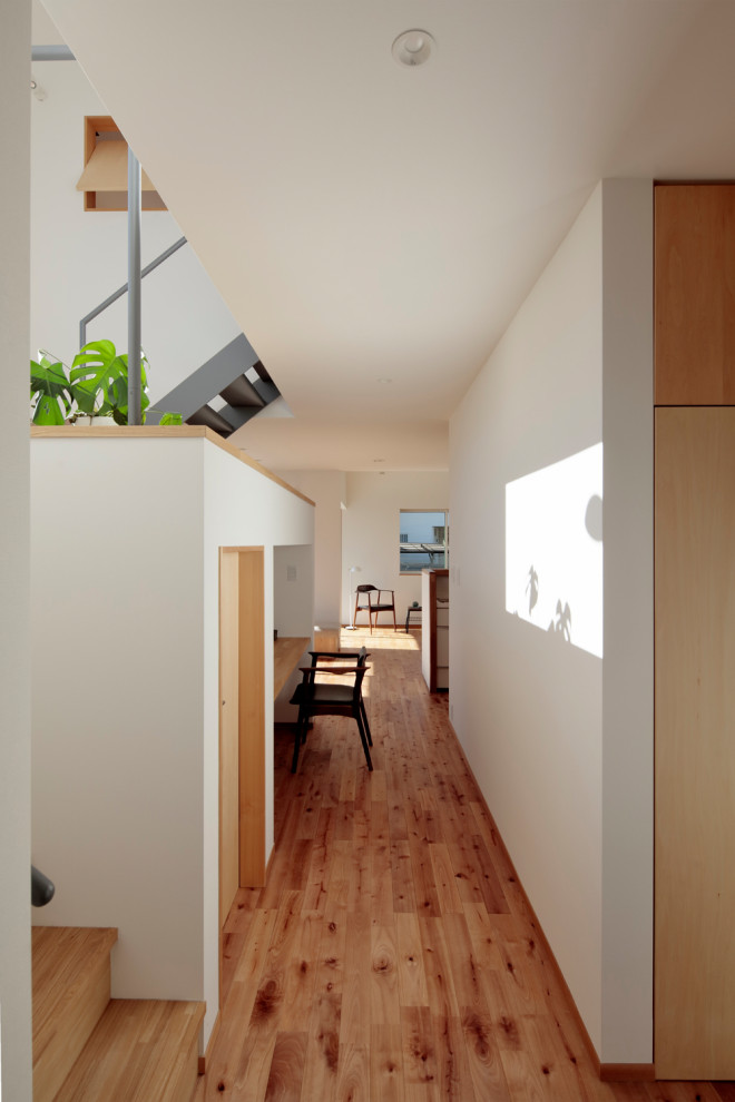 Inspiration för mellanstora minimalistiska hallar, med vita väggar, plywoodgolv och brunt golv