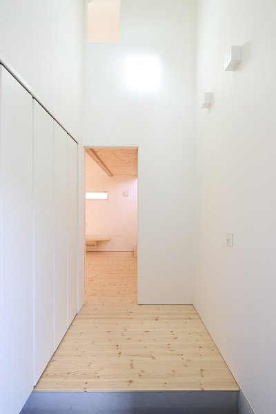 Foto på en mellanstor hall, med vita väggar, ljust trägolv och beiget golv
