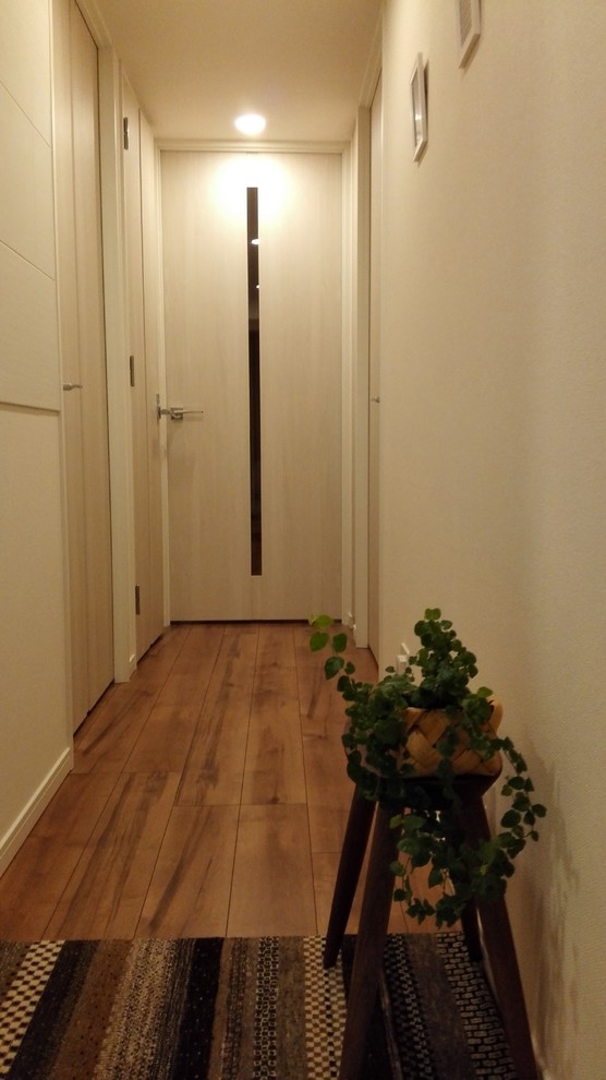 Inspiration pour un petit couloir nordique avec un mur blanc, un sol en contreplaqué et un sol marron.