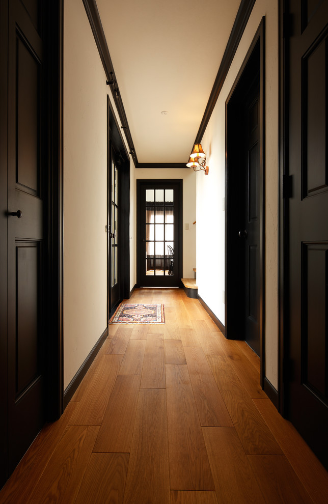 Example of a mid-century modern medium tone wood floor and brown floor hallway design in Other with white walls