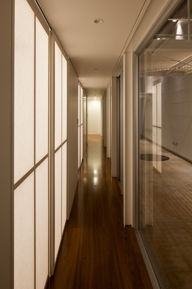 Foto på en funkis hall, med vita väggar, mellanmörkt trägolv och brunt golv