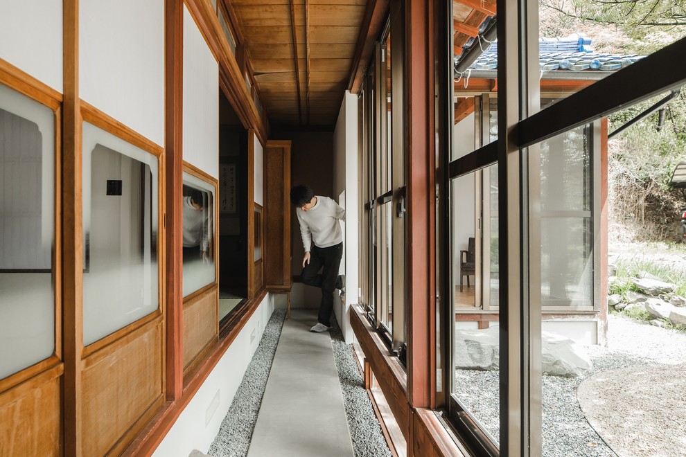 Ejemplo de recibidores y pasillos asiáticos extra grandes con paredes marrones, suelo de cemento y suelo gris