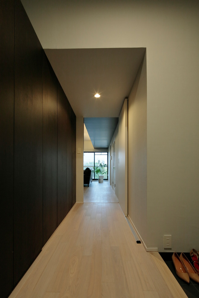 Idées déco pour un couloir moderne avec un mur blanc, un sol en contreplaqué et un sol beige.