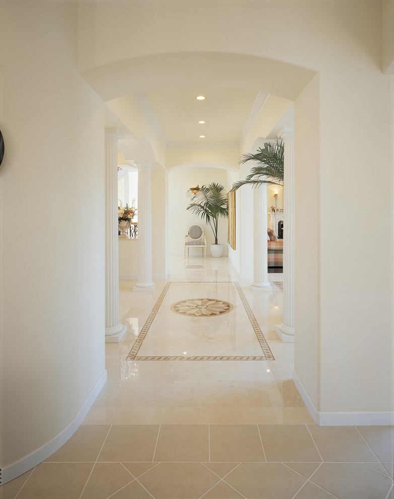 На фото: огромный коридор в средиземноморском стиле с белыми стенами, мраморным полом и бежевым полом