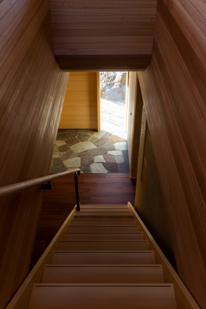 Inredning av en skandinavisk liten hall, med beige väggar, mörkt trägolv och brunt golv