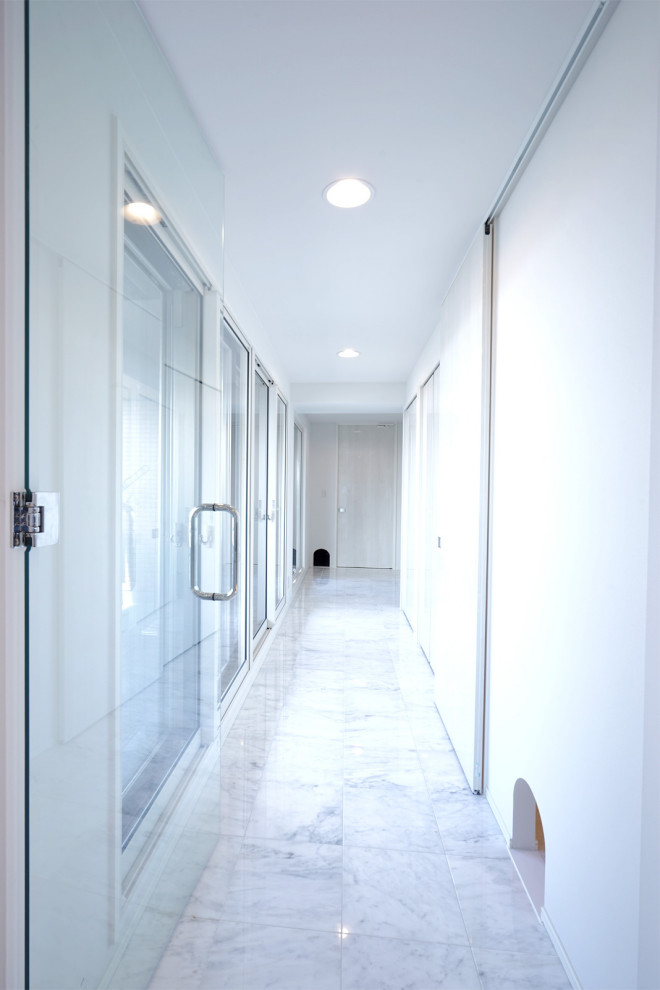 Modern inredning av en mellanstor hall, med vita väggar, marmorgolv och vitt golv