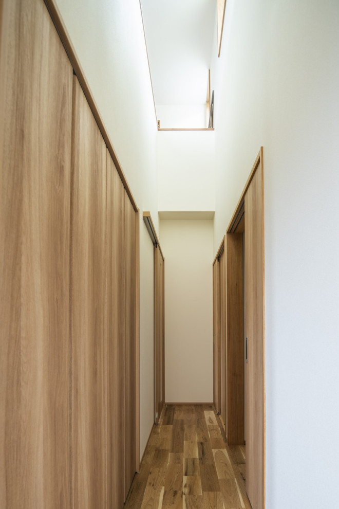Bild på en mellanstor funkis hall, med vita väggar, ljust trägolv och beiget golv
