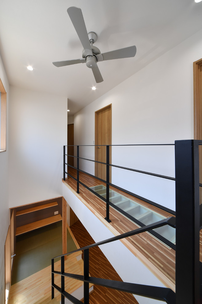 Cette image montre un petit couloir design avec un mur blanc, un sol en contreplaqué et un sol marron.