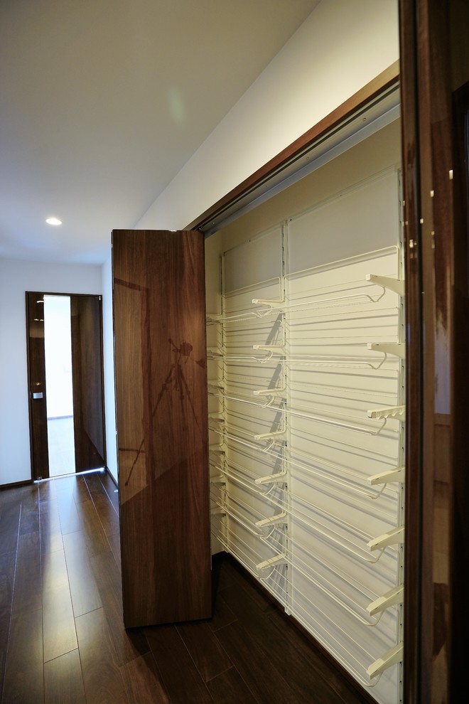Стильный дизайн: большая гардеробная комната унисекс с полом из фанеры, коричневым полом и потолком с обоями - последний тренд