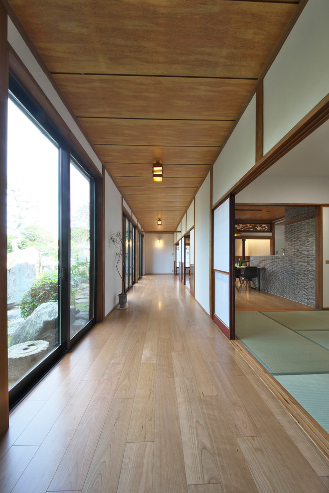 Ejemplo de recibidores y pasillos asiáticos con paredes blancas, suelo de madera en tonos medios y suelo marrón