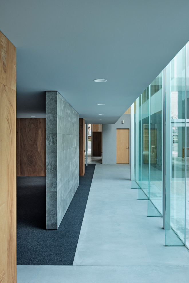 Свежая идея для дизайна: огромный коридор в стиле модернизм с серыми стенами, бетонным полом, серым полом, потолком с обоями и панелями на части стены - отличное фото интерьера