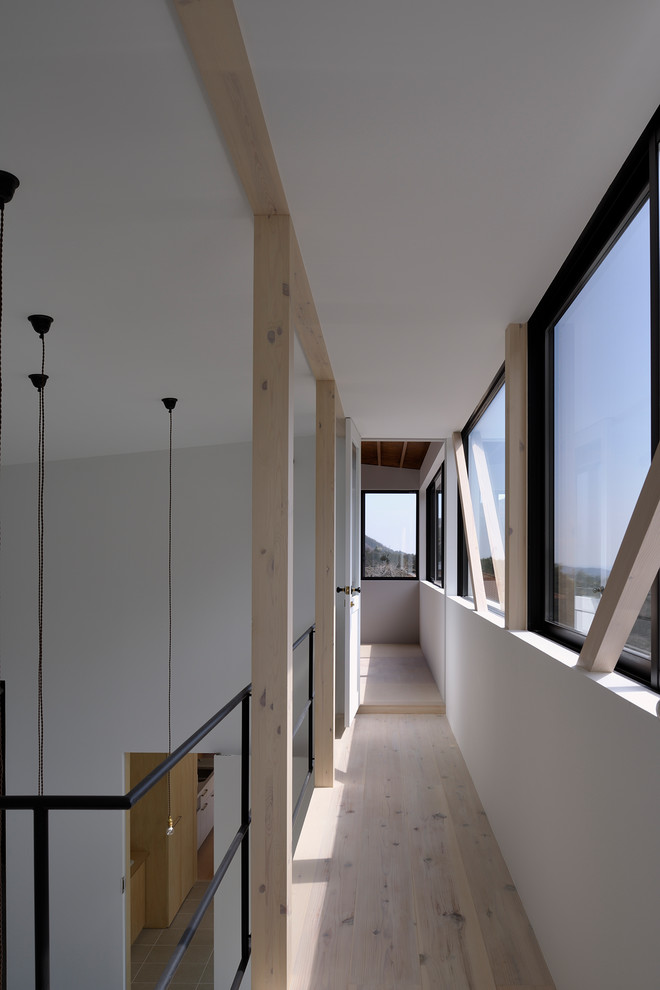 Ejemplo de recibidores y pasillos modernos con paredes blancas, suelo de madera clara y suelo beige