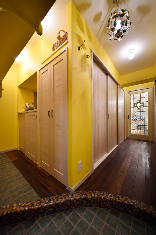 他の地域にあるコンテンポラリースタイルのおしゃれな廊下 (黄色い壁、濃色無垢フローリング、茶色い床) の写真