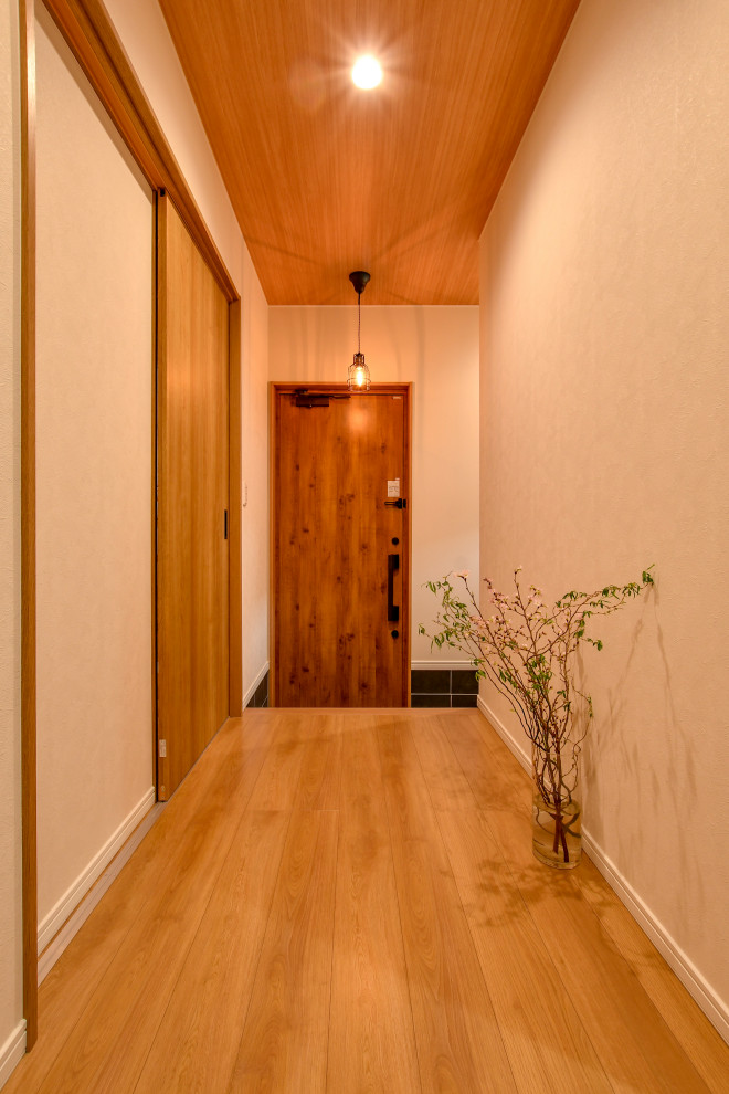 Bild på en minimalistisk hall, med vita väggar, mellanmörkt trägolv och brunt golv