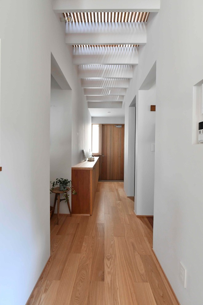 Diseño de recibidores y pasillos nórdicos con paredes blancas, suelo de madera en tonos medios y suelo marrón