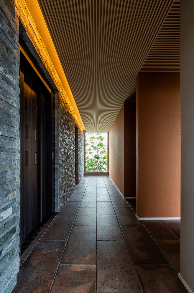 Imagen de recibidores y pasillos minimalistas grandes con paredes grises, suelo de baldosas de porcelana y suelo marrón