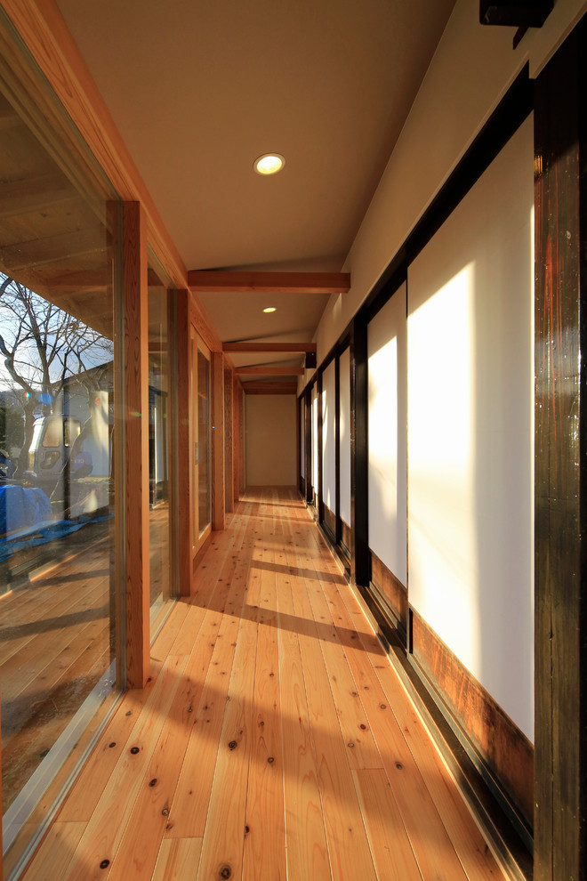 Ispirazione per un ingresso o corridoio etnico di medie dimensioni con pareti bianche, pavimento in legno massello medio e pavimento marrone