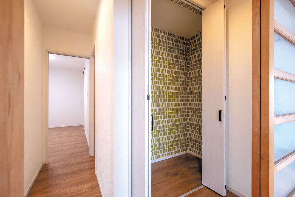 Cette image montre un petit couloir design avec un sol en contreplaqué, un sol marron et un mur multicolore.
