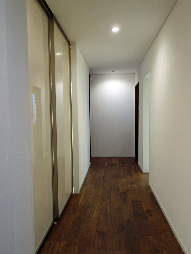Exempel på en hall, med vita väggar, plywoodgolv och brunt golv