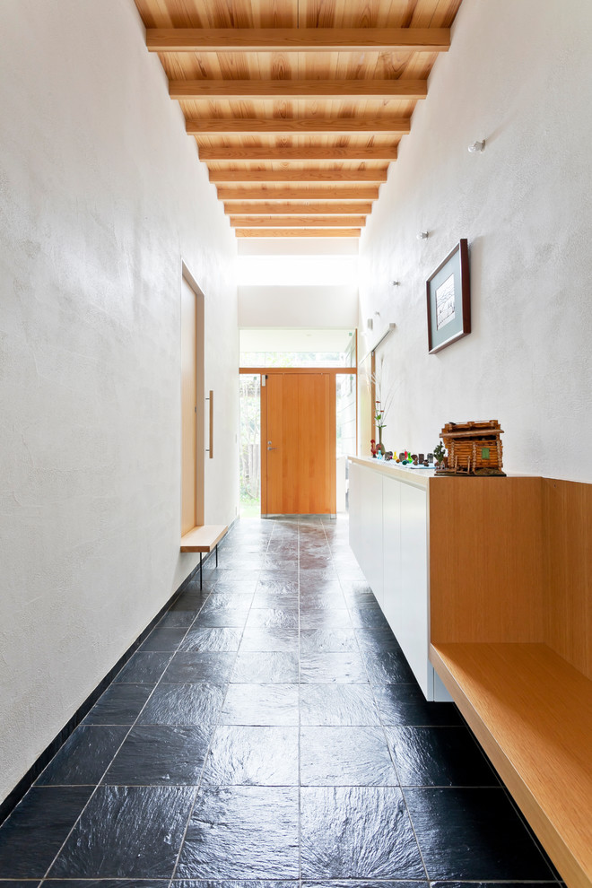 На фото: большой коридор в современном стиле с белыми стенами, полом из сланца и черным полом с