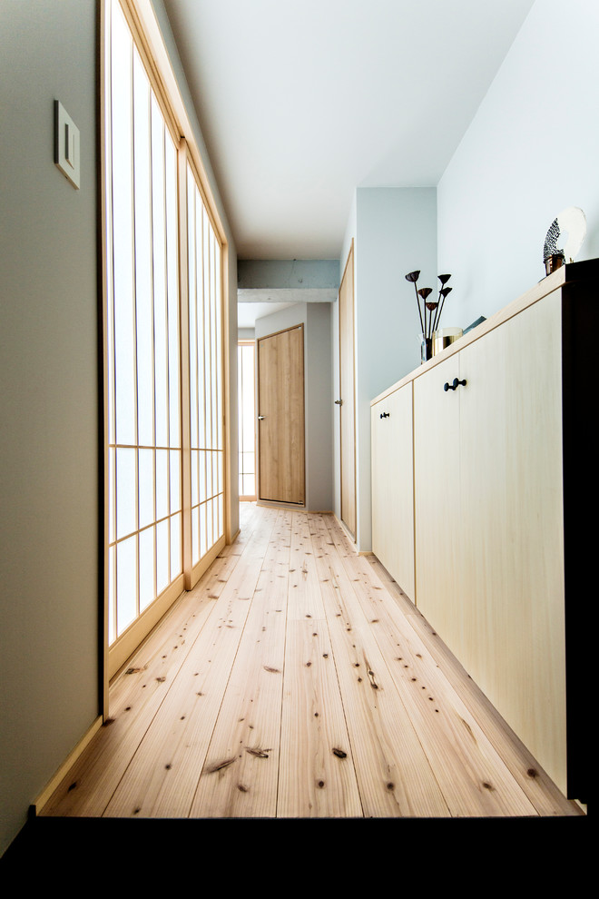 Example of a zen medium tone wood floor and brown floor hallway design with blue walls