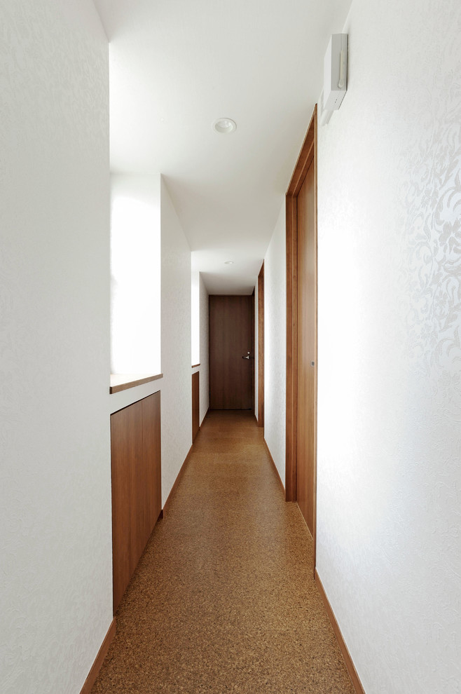 他の地域にある広いモダンスタイルのおしゃれな廊下 (白い壁、コルクフローリング、茶色い床) の写真