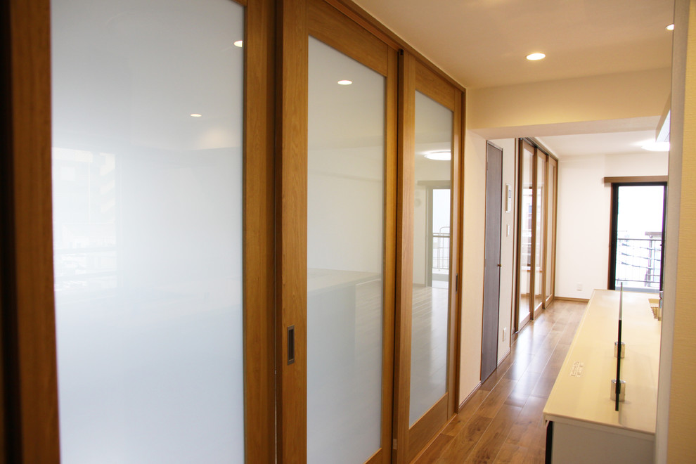 Example of a danish medium tone wood floor hallway design in Tokyo with white walls