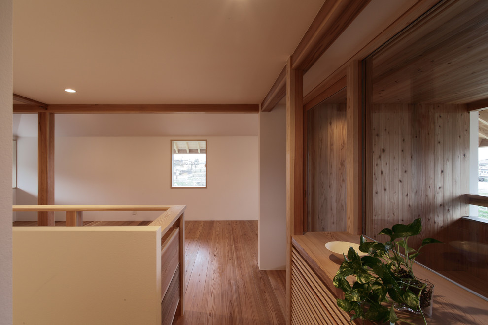 Aménagement d'un petit couloir scandinave avec un mur blanc, un sol en bois brun et un sol marron.