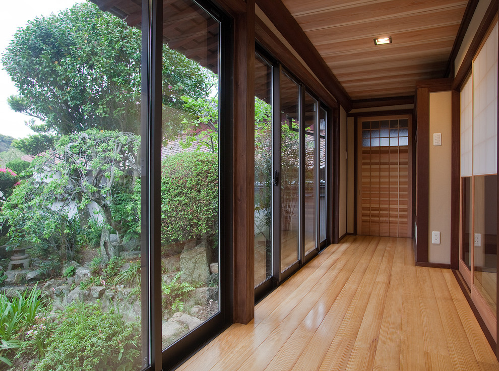 Aménagement d'un couloir asiatique avec un mur marron, un sol en bois brun et un sol marron.