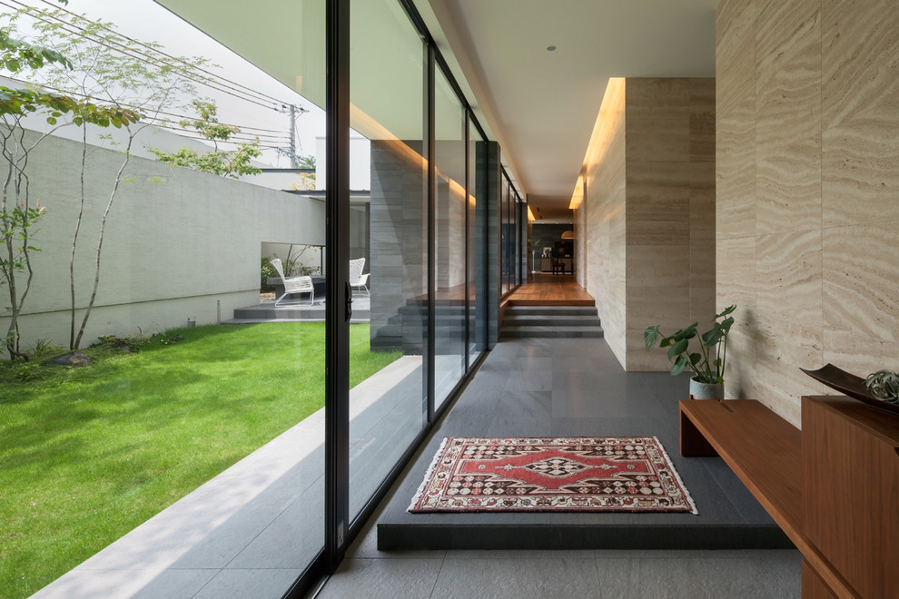 Ispirazione per un ingresso o corridoio minimalista con pareti beige e pavimento nero