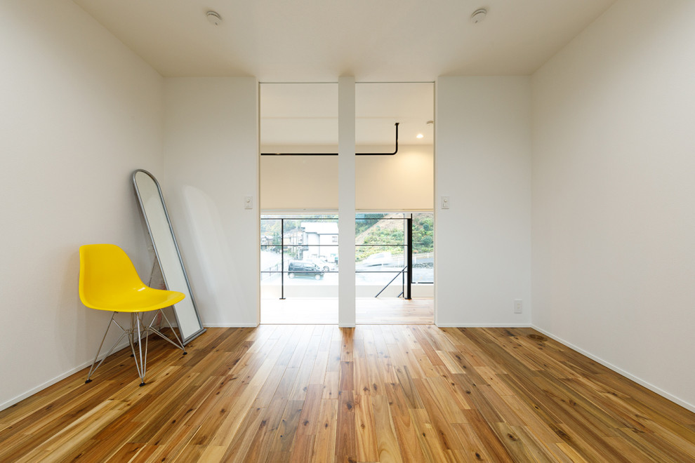 Aménagement d'un couloir moderne de taille moyenne avec parquet clair, un mur blanc et un sol marron.