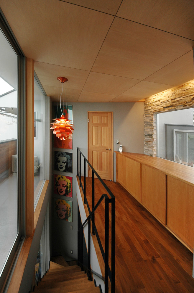 Immagine di un ingresso o corridoio minimalista con pareti grigie, pavimento in legno massello medio e pavimento marrone