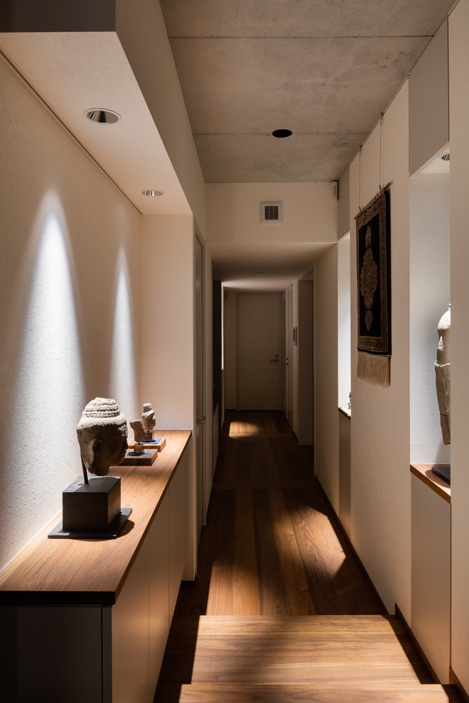 Imagen de recibidores y pasillos asiáticos con paredes blancas y suelo de madera oscura