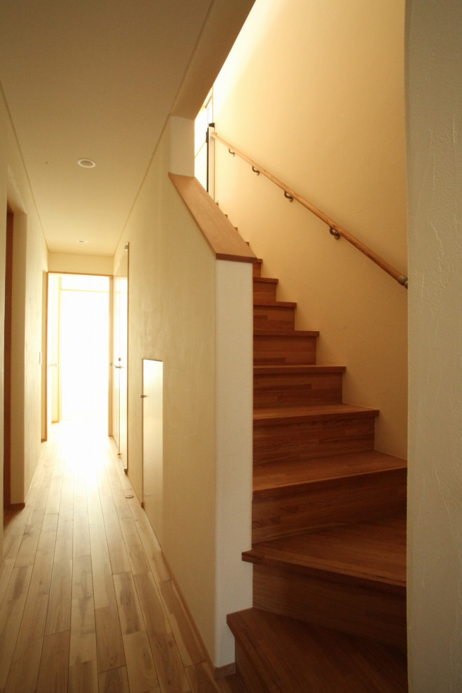 Cette photo montre un petit couloir moderne avec un mur blanc, un sol en bois brun et un sol marron.