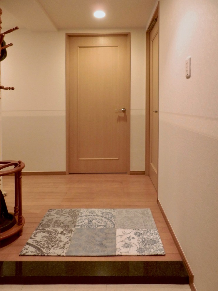Exempel på en liten klassisk hall, med beige väggar, plywoodgolv och brunt golv