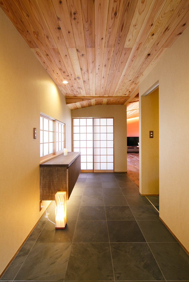 Diseño de recibidores y pasillos de estilo zen con paredes amarillas y suelo negro