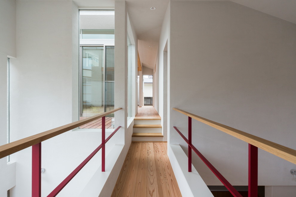 Пример оригинального дизайна: коридор в современном стиле с белыми стенами, паркетным полом среднего тона и коричневым полом