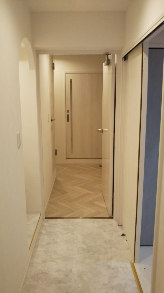 Cette image montre un couloir de taille moyenne avec un mur blanc, un sol en vinyl et un sol blanc.