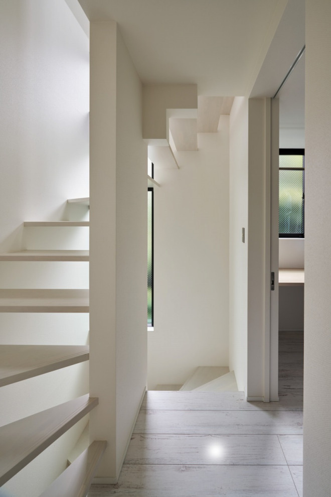 На фото: коридор в стиле модернизм с белыми стенами, полом из фанеры и белым полом с