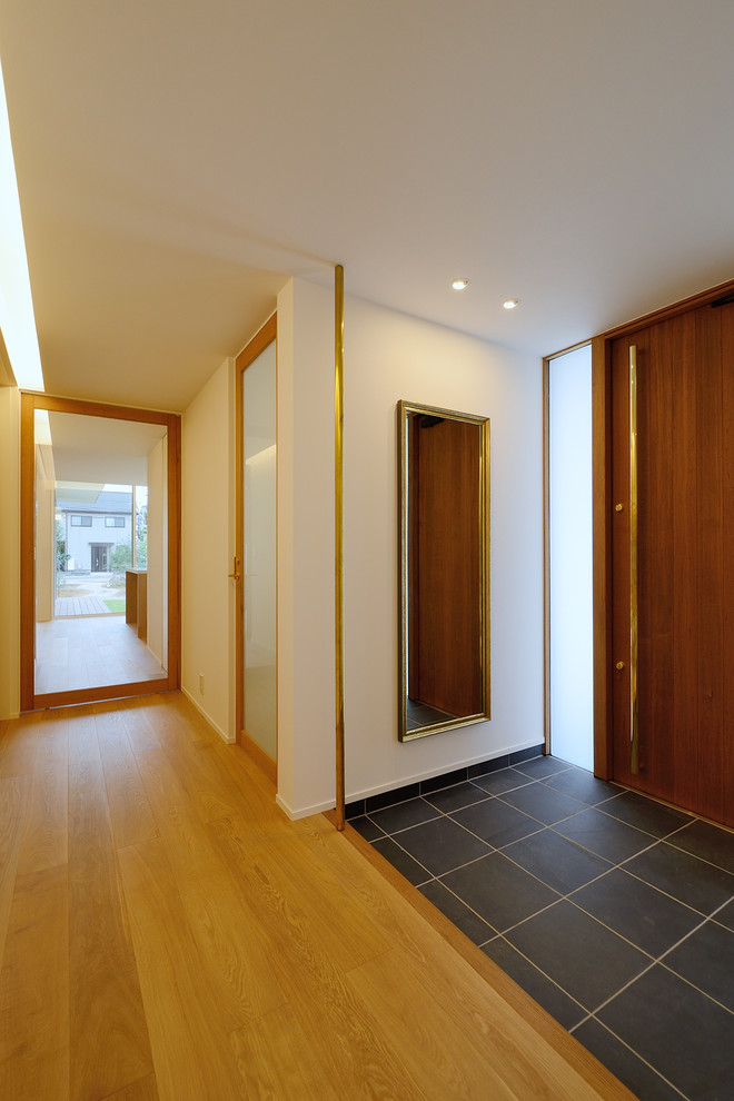 Cette image montre une entrée nordique de taille moyenne avec un mur blanc, un sol en bois brun, un sol marron, un couloir, une porte simple, une porte en bois foncé, un plafond en papier peint et du papier peint.