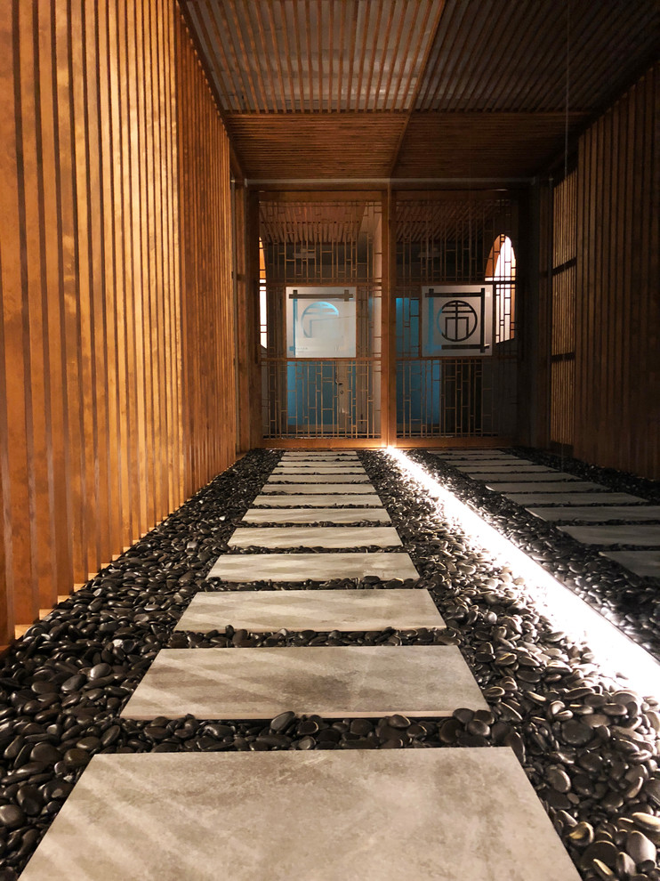Exempel på en mellanstor asiatisk hall, med bruna väggar, klinkergolv i porslin och svart golv