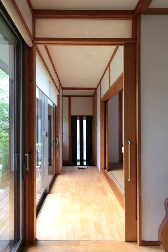 Ispirazione per un ingresso o corridoio chic di medie dimensioni con pareti bianche, pavimento in legno massello medio e pavimento beige