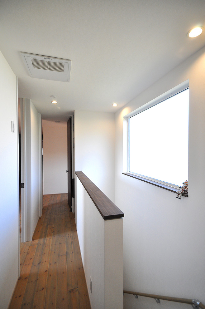 Immagine di un ingresso o corridoio moderno con pareti bianche, pavimento in legno massello medio e pavimento marrone