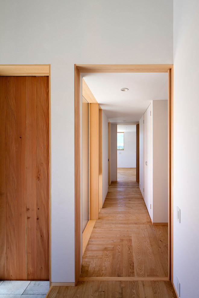 Immagine di un piccolo ingresso o corridoio scandinavo con pareti nere e pavimento in legno massello medio