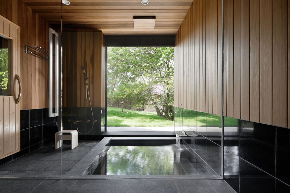 Esempio di una stanza da bagno padronale etnica con vasca idromassaggio, doccia doppia, piastrelle nere e piastrelle in pietra